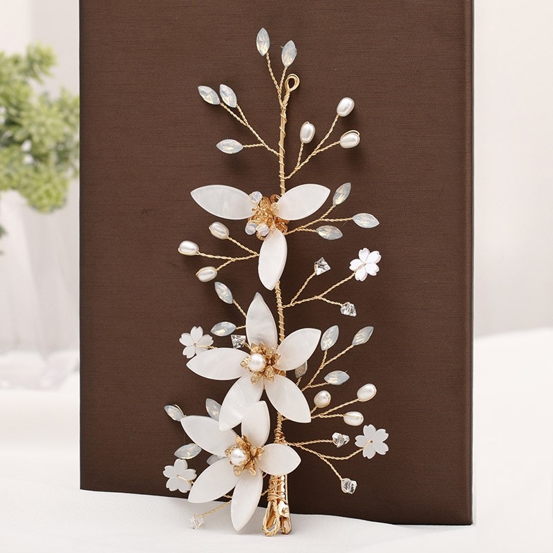 Close flores brancas acetinadas e ramos dourados para cabelo noiva