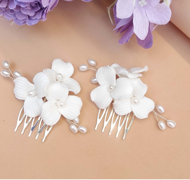 Close-up de dois pentes de grinalda de noiva artesanais de porcelana fria com flores brancas e pérolas delicadas