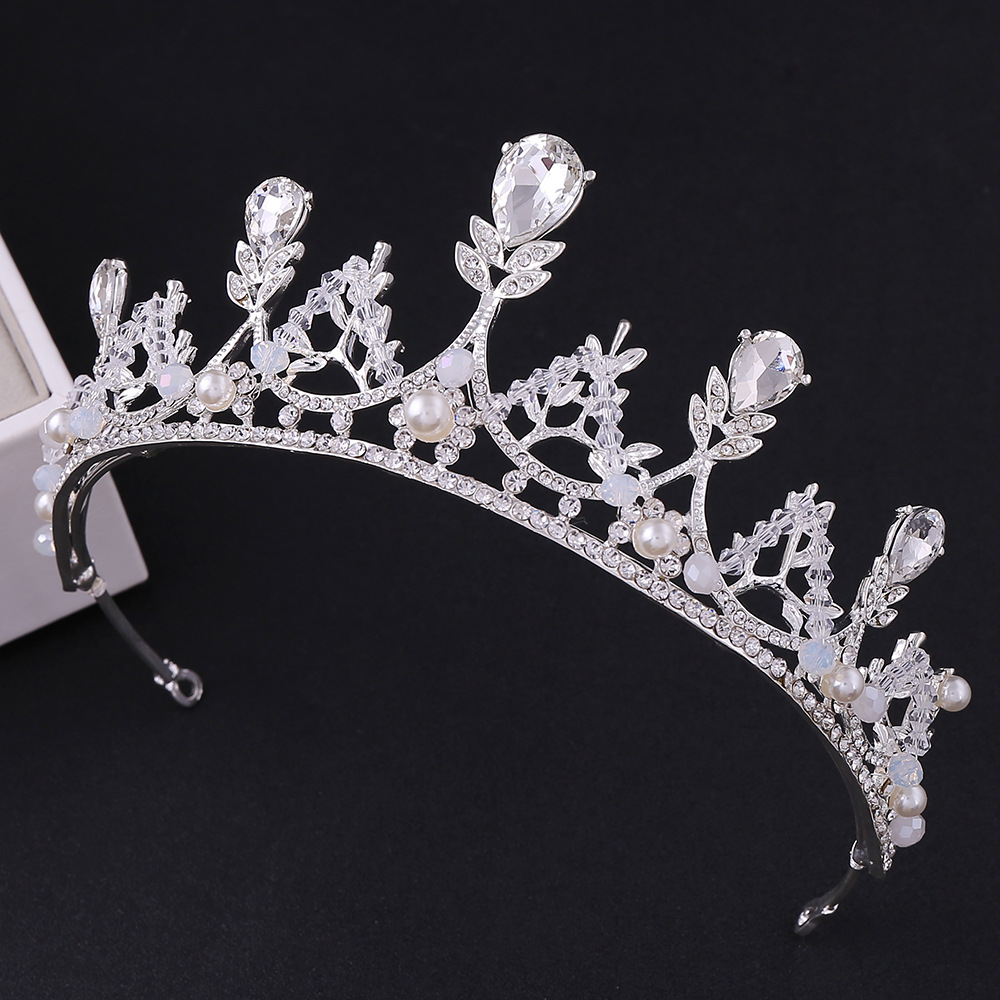 Coroa prateada de luxo para noiva ou debutante, vista de frente em fundo preto. A peça possui cristais em formato de gota e redondos, intercalados com pérolas brancas delicadas. Altura de 5,5cm.