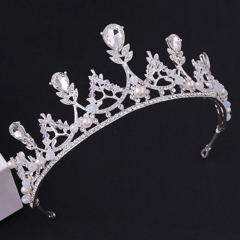 Coroa prateada de luxo para noiva ou debutante, vista de frente em fundo preto. A peça possui cristais em formato de gota e redondos, intercalados com pérolas brancas delicadas. Altura de 5,5cm.